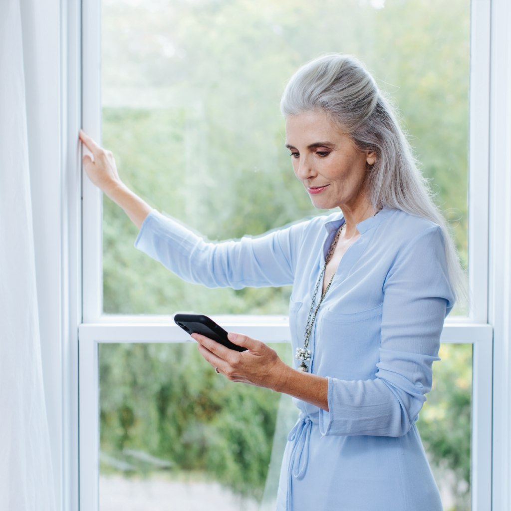 Woman looks at phone in front of window